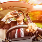 Man drinking out of a flask while drunk driving Man drinking out of a flask while drunk driving