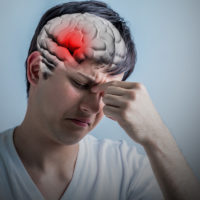 Brain image of a traumatic brain injury depicted in red shown in physical human head Brain image of a traumatic brain injury depicted in red shown in physical human head