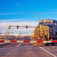 A train crosses a busy street at a railroad crossing