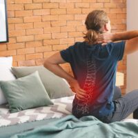 Young man suffering from back pain at home