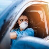 Young woman driving car with protective mask on her face. Healthcare, virus protection, allergy protection concept. Young woman driving car with protective mask on her face. Healthcare, virus protection, allergy protection concept.
