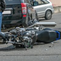 broken motorcycle closeup beside the car. an accident on the road in the city on a sunny day involving a motorcycle and a car. broken motorcycle closeup beside the car. an accident on the road in the city on a sunny day involving a motorcycle and a car.