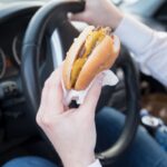 Man eating an hamburger while driving car