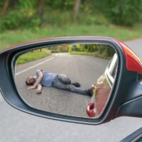 Hit and run concept. View on injured man on road in rear mirror Hit and run concept. View on injured man on road in rear mirror
