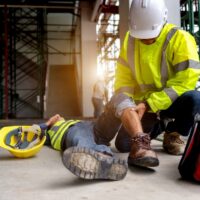 A person helps an injured construction worker, representing the effects and causes of WV construction accidents. A person helps an injured construction worker, representing the effects and causes of WV construction accidents.