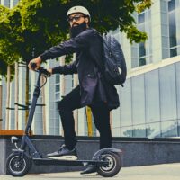 A man posing on electric scooter.