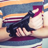 Man with hand in orthopedic black orthosis Man with hand in orthopedic black orthosis