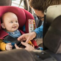 Father fasten his little baby in the car seat