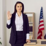 American witness takes an oath before giving a testimony. A jury member standing near a male judge in the court room swears on the Bible that she will tell the truth. Law and justice in the US concept