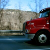A red semi truck on a mountain road represents the need for West Virginia truck accident lawyers when someone is injured.